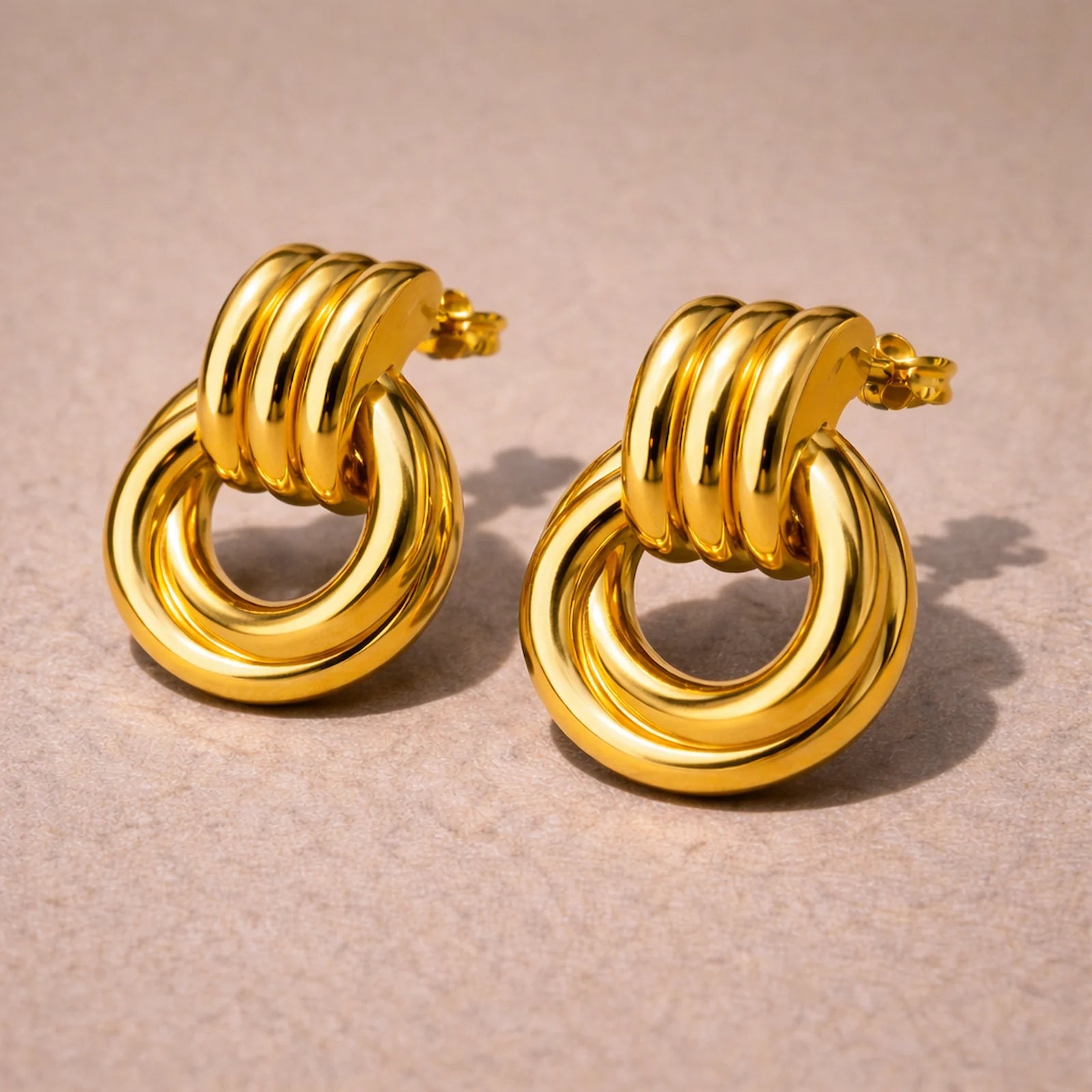 Pair of gold hoop earrings on a beige background