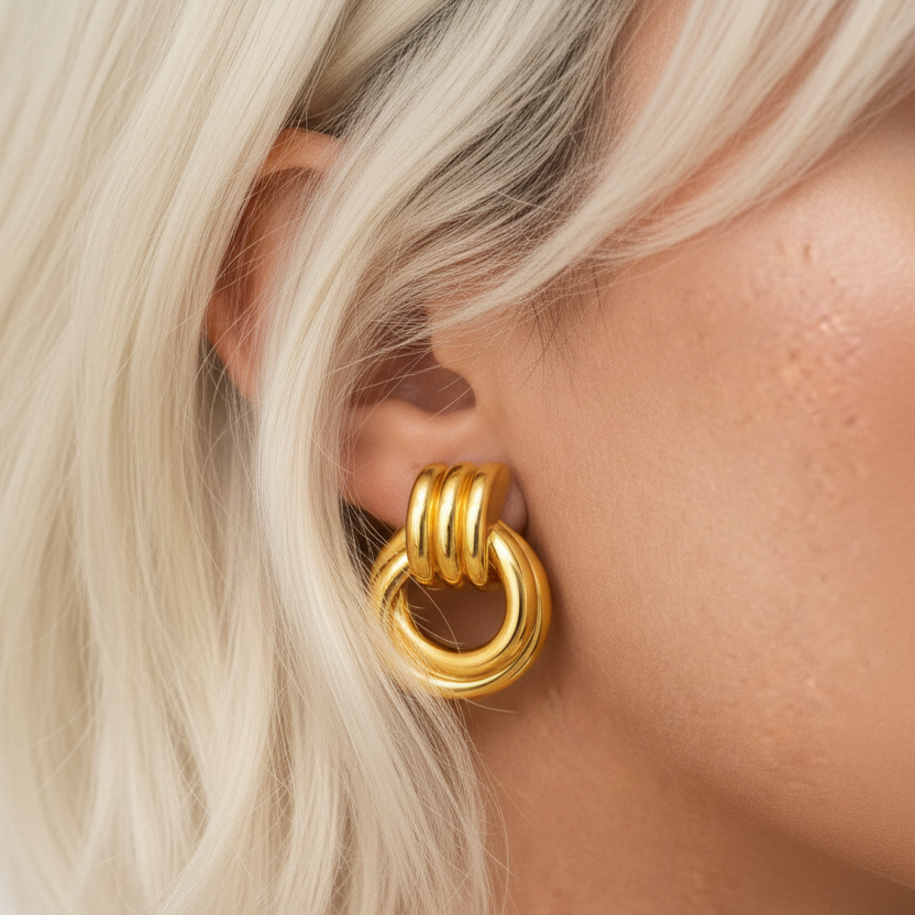 Gold hoop earring worn by a person with white hair.