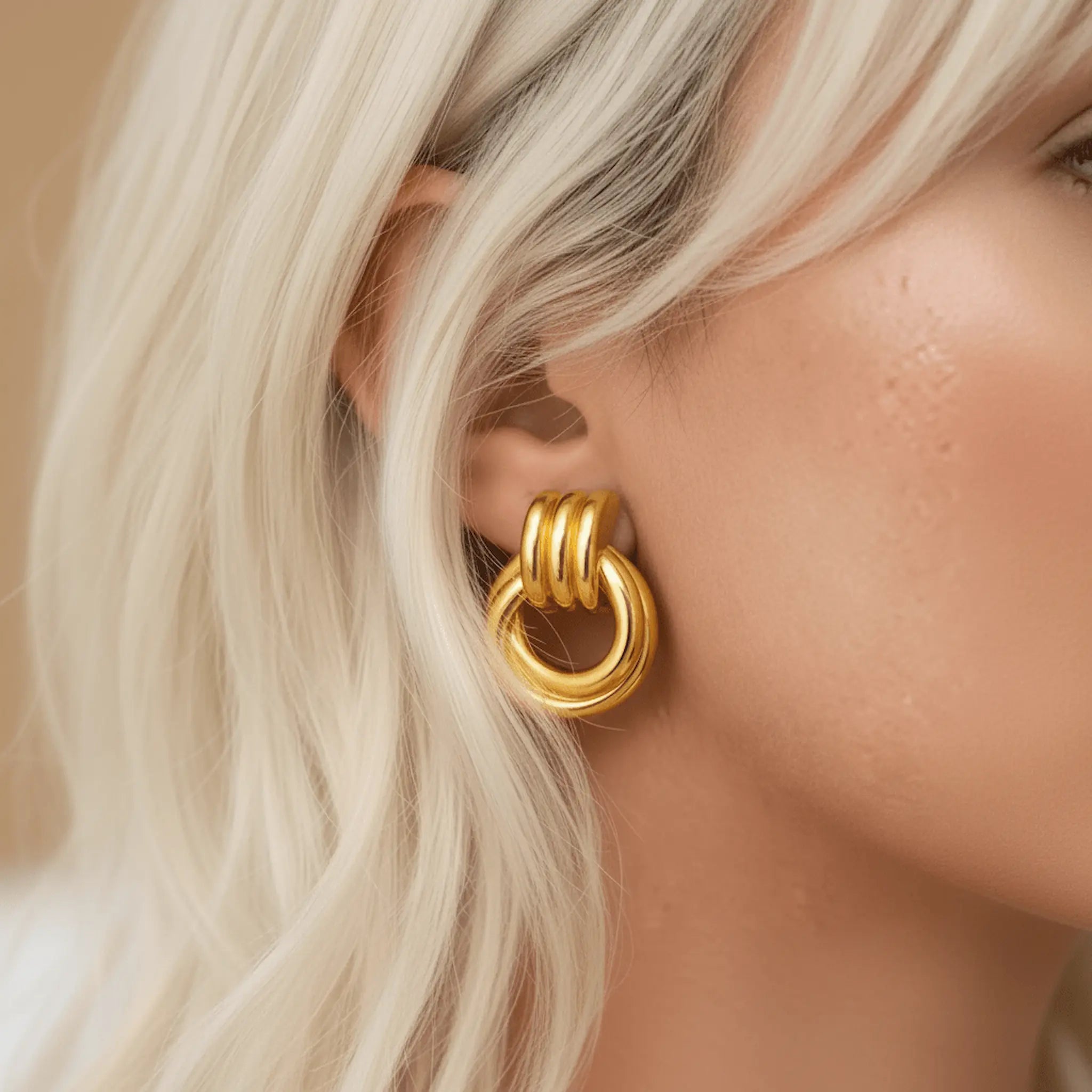 Close-up of a person wearing a gold hoop earring with a neutral 