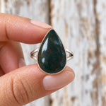 Fingers holding the silver bloodstone teardrop ring