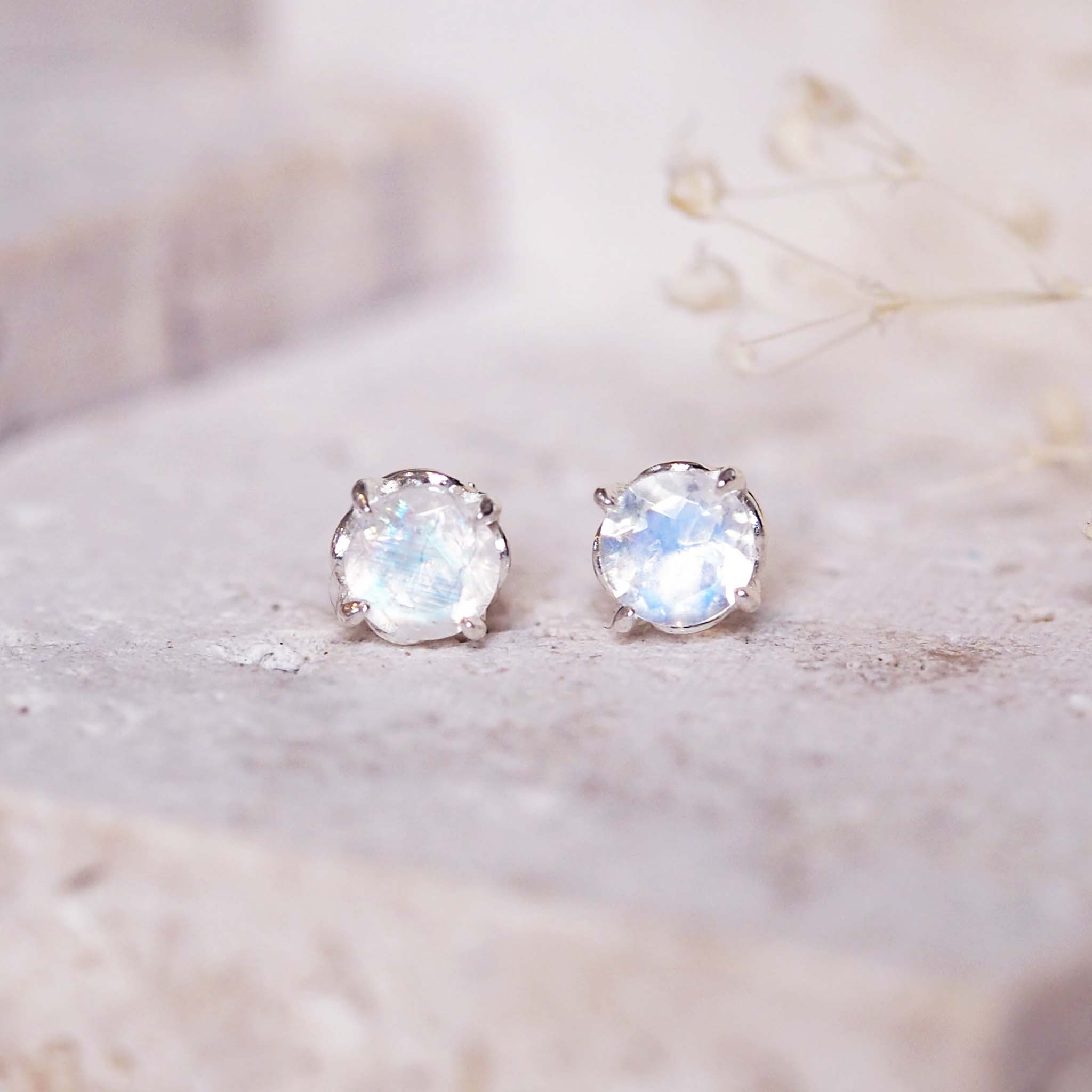 indie and harper - Pair of silver stud earrings with a clear gemstone on a light background