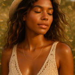 Woman wearing a straw hat and crochet top in a field, with a dainty gold chain necklace from indie and harper