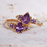 Gold ring with purple gemstones on a textured surface