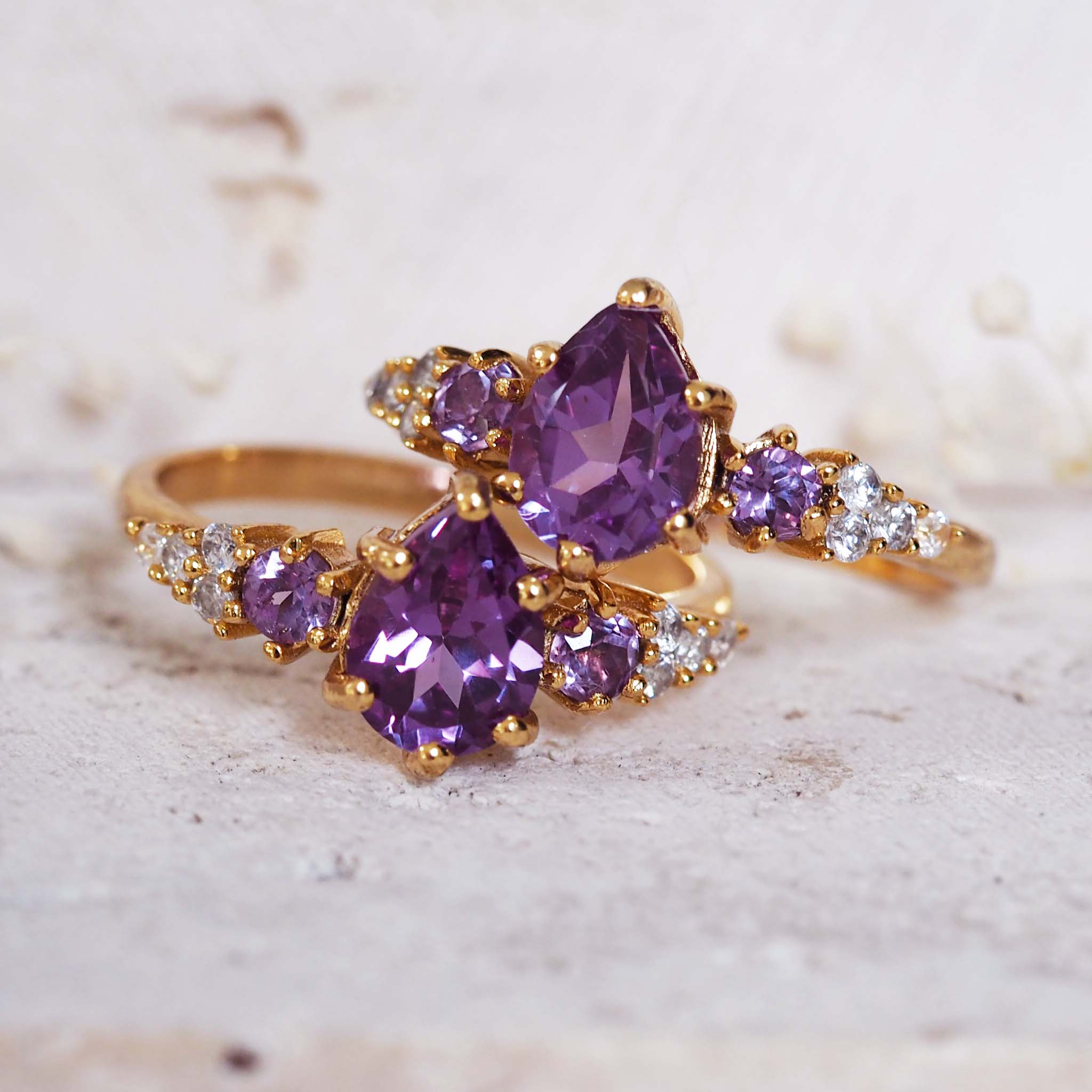 Gold ring with purple gemstones on a textured surface