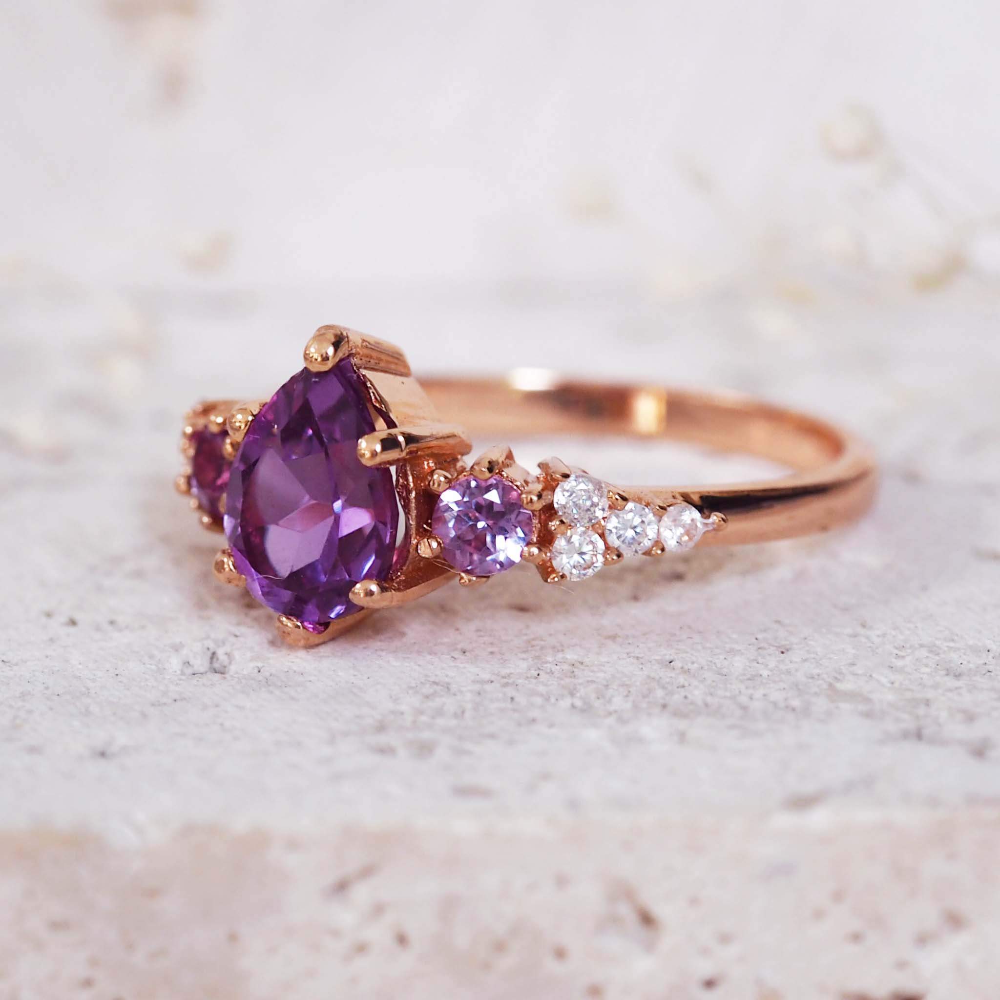 Rose gold ring with a purple gemstone on a light background