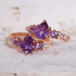Rose gold ring with purple gemstones on a textured surface