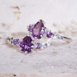Purple gemstone ring with silver band on a textured surface