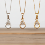 Three teardrop-shaped pendants on chains against a neutral background