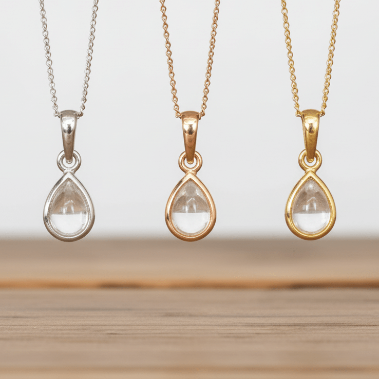 Three teardrop-shaped pendants on chains against a neutral background