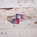 indie and harper - Silver ring with rectangular multicoloured gemstones on a textured beige surface
