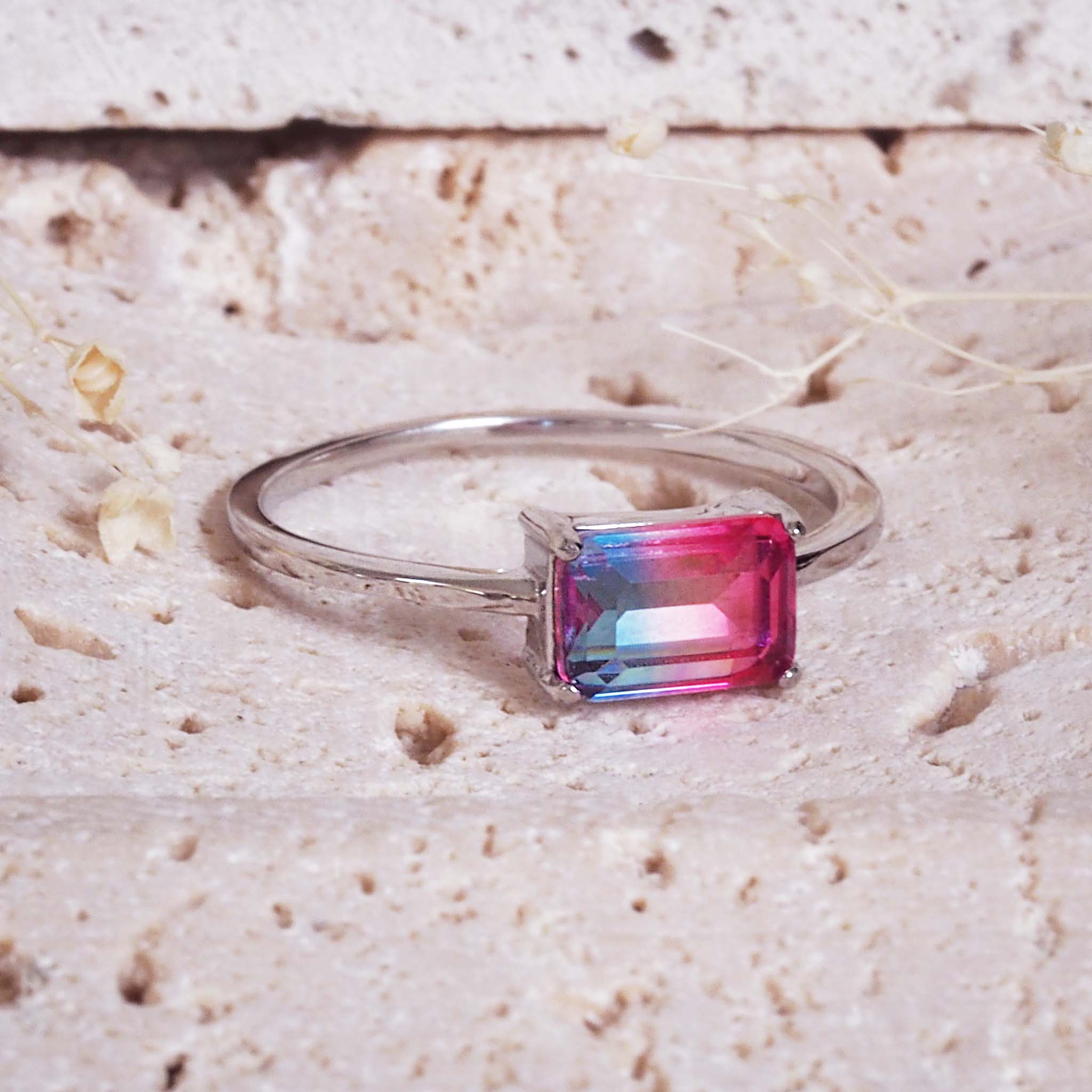 Silver ring with a pink gemstone on a textured beige surface