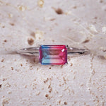 Ring with a multicolored gemstone on a textured beige surface