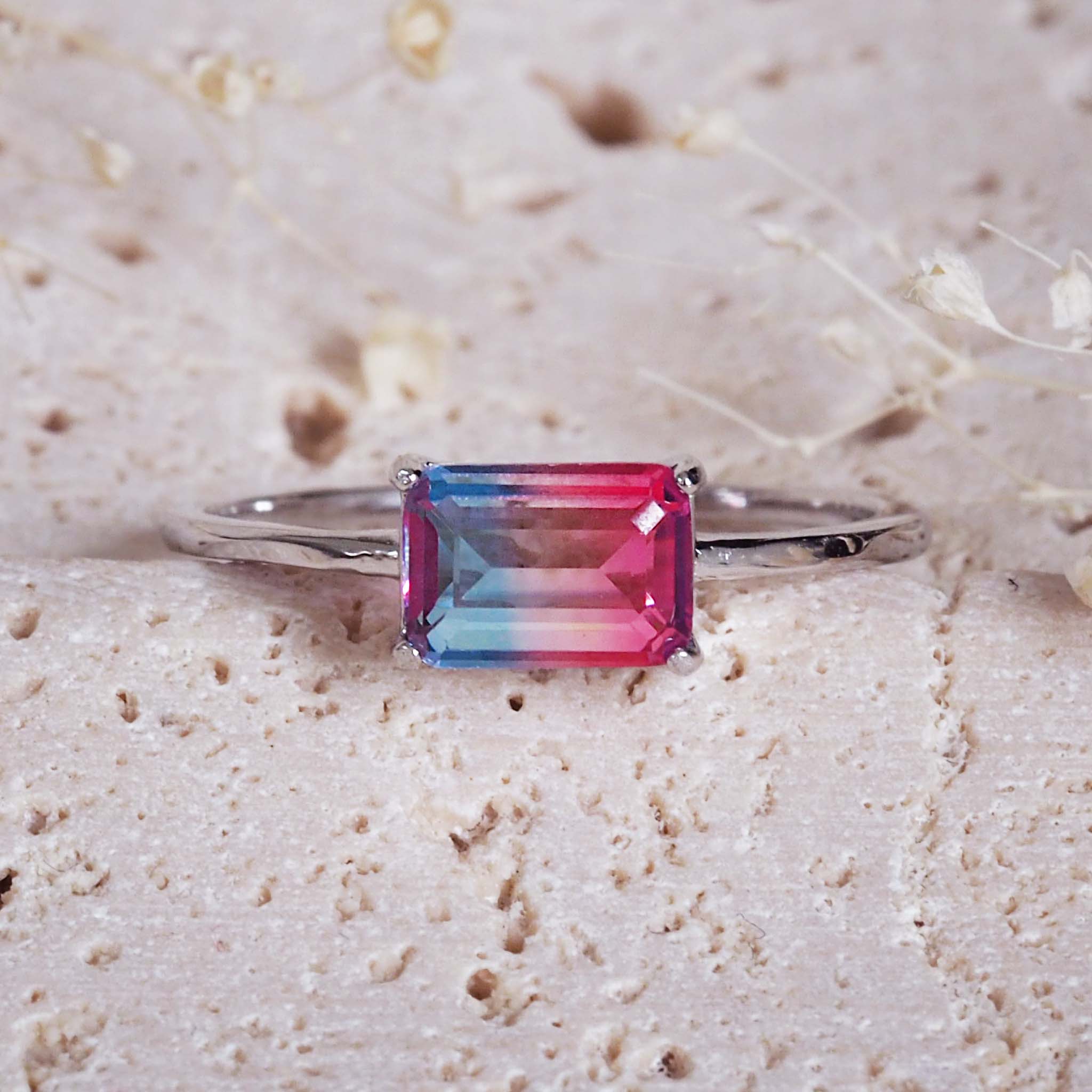 Ring with a multicolored gemstone on a textured beige surface