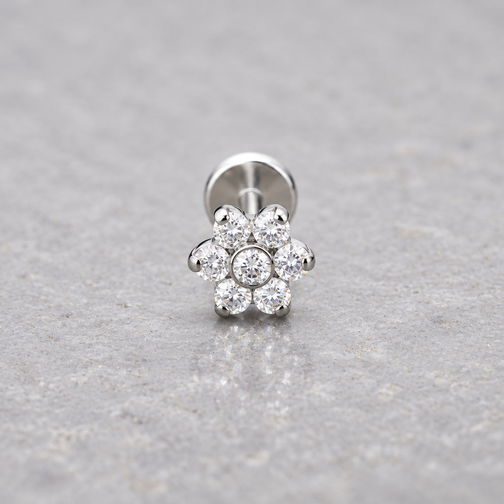Silver flower flat back earring with cubic zirconia on a grey surface
