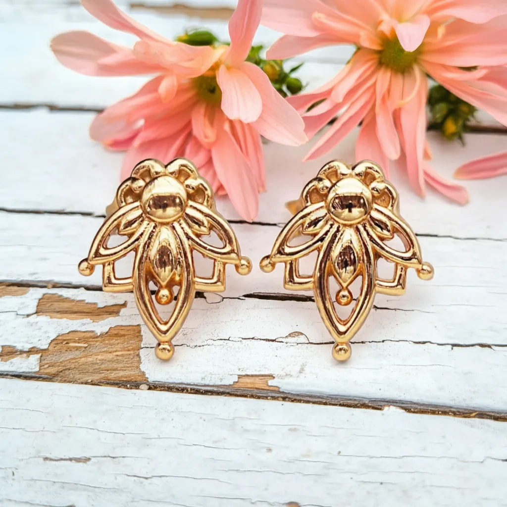 dainty gold lotus flower stud earrings on a piece of wood - by indie and harper australia