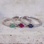 Three silver rings with colored gemstones on a textured surface