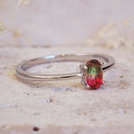 Silver ring with a red gemstone on a textured beige background