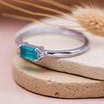 Silver ring with a blue gemstone on a beige stone surface with dried grass in the background