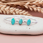 Silver bracelet with turquoise stones on a pebble with dried wheat in the background