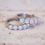 Two silver rings with opal stones on a textured surface