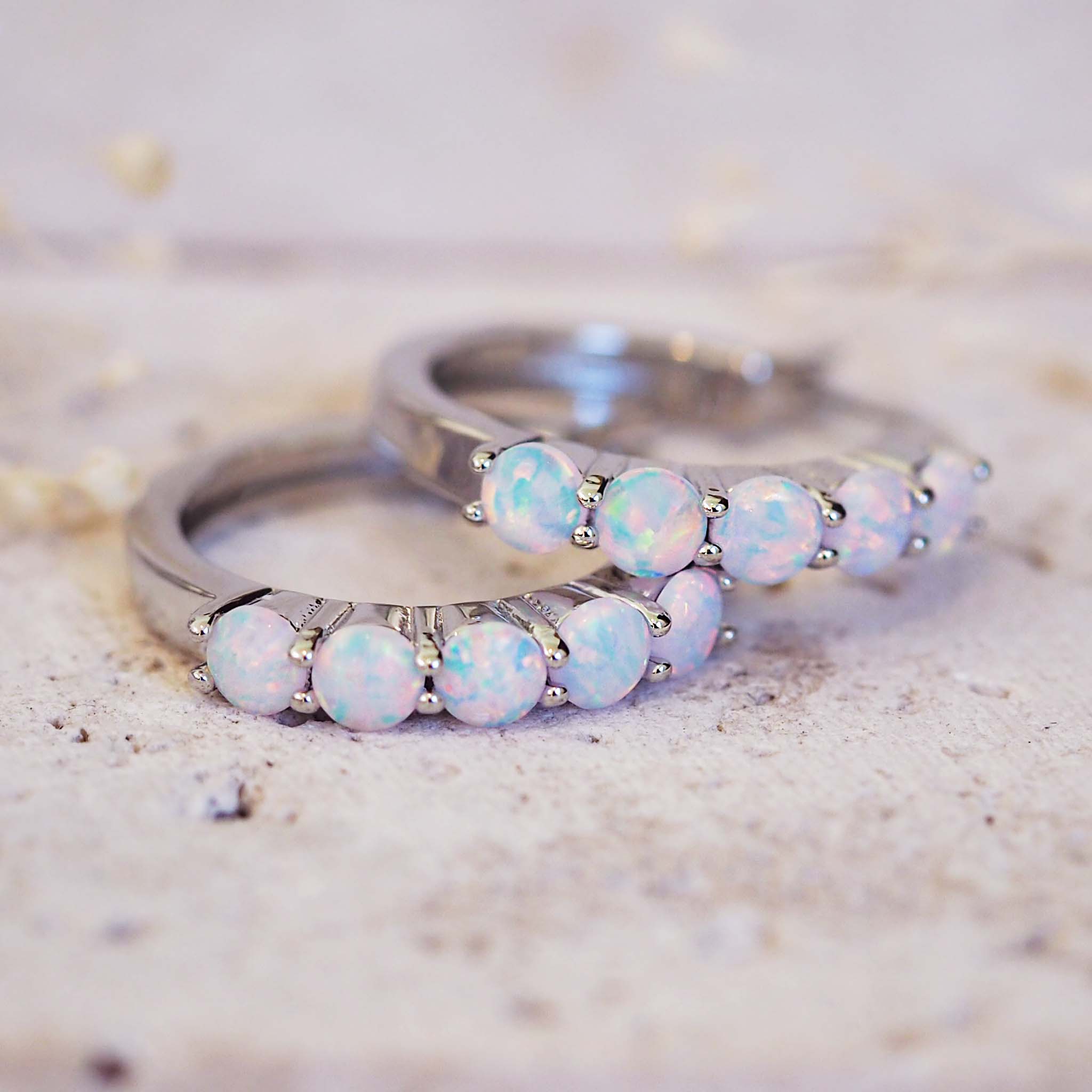 Two silver rings with opal stones on a textured surface