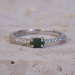 Silver ring with a green gemstone on a textured beige surface
