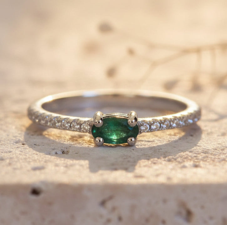 Silver ring with a green gemstone on a textured beige surface