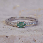 Silver ring with a green gemstone on a textured beige background