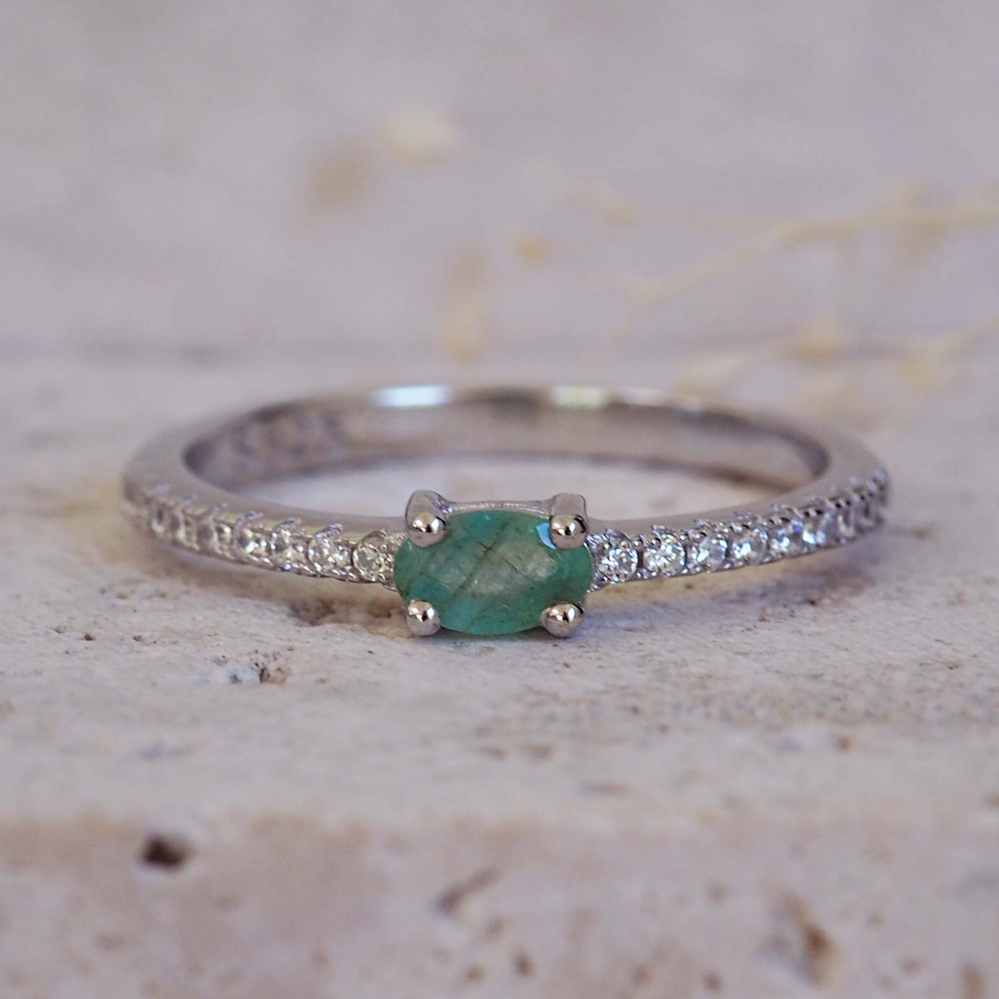 Silver ring with a green gemstone on a textured beige background