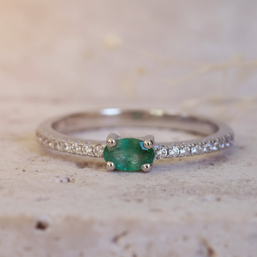 Silver ring with a green gemstone on a textured beige background
