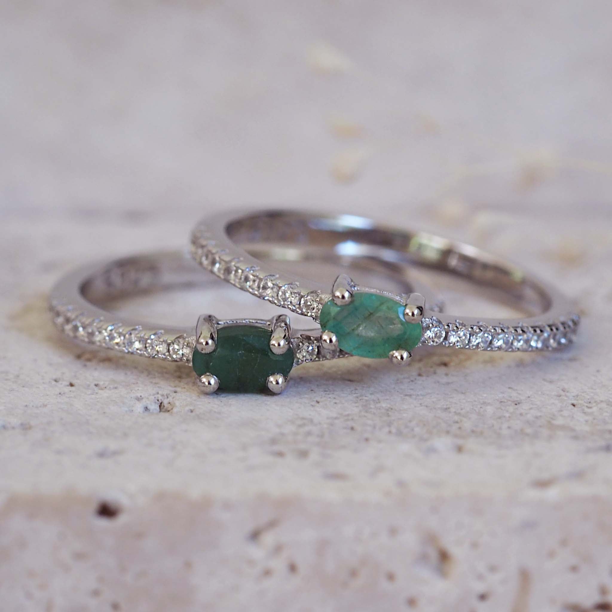 Two silver rings with green gemstones on a textured surface