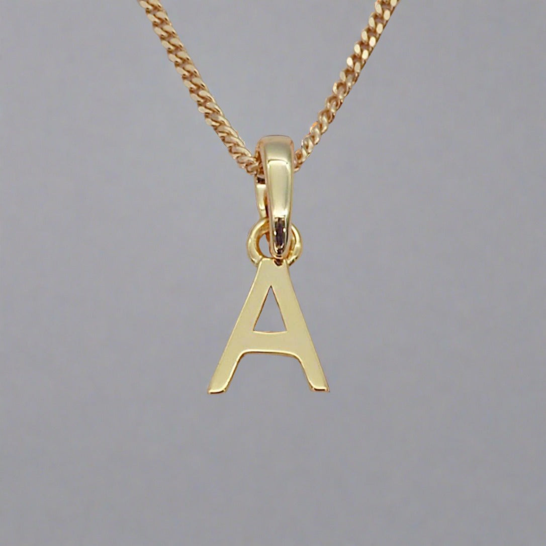 Gold necklace with a pendant shaped like the letter 'A' on a gray background
