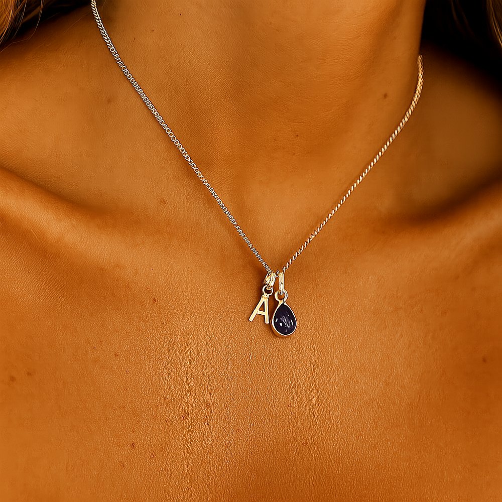 Gold Initial Necklace with a september birthstone sapphire pendant being worn 