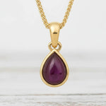 gold pendant with a red garnet gemstone