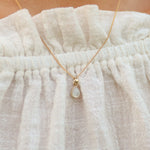 Necklace with a teardrop pendant on a textured fabric background