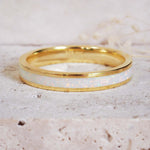 Gold ring with a white interior on a textured beige background