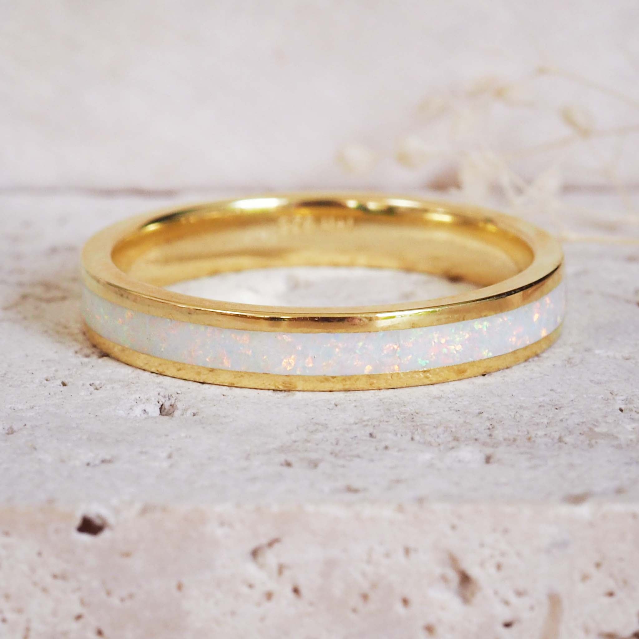 Gold ring with a white interior on a textured beige background