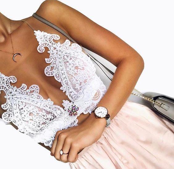 Close-up of a person wearing a lace top and pink skirt with a watch on a white background