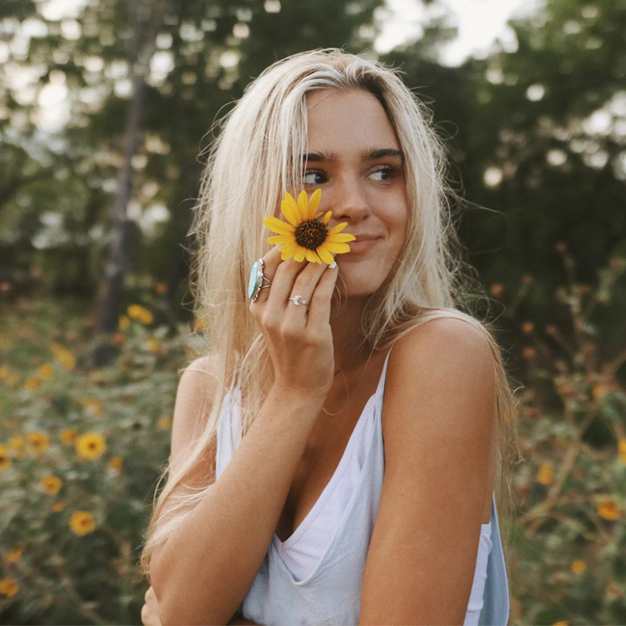 girl with blonde hair holding a flower wearing boho jewellery