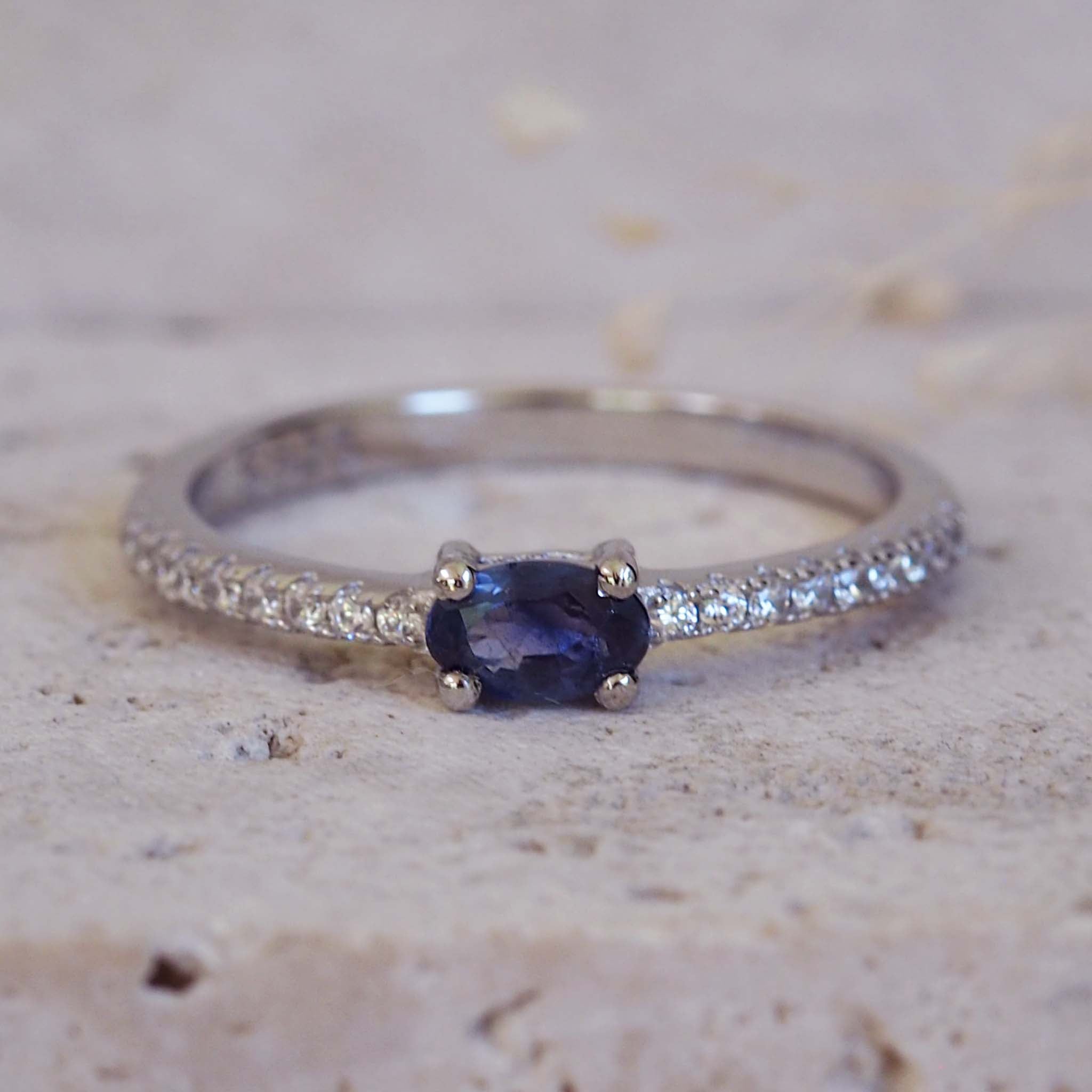 Ring with a blue gemstone and diamond accents on a textured surface
