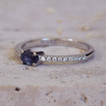 Silver ring with a blue gemstone and small diamonds on a beige surface