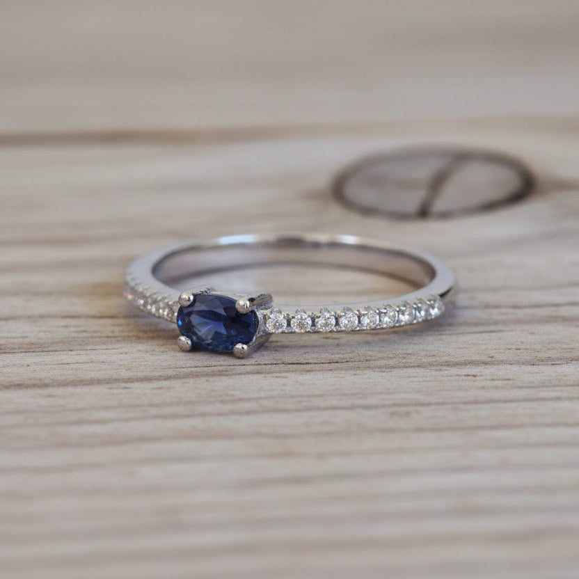 Silver ring with a blue gemstone and small diamonds on a beige surface