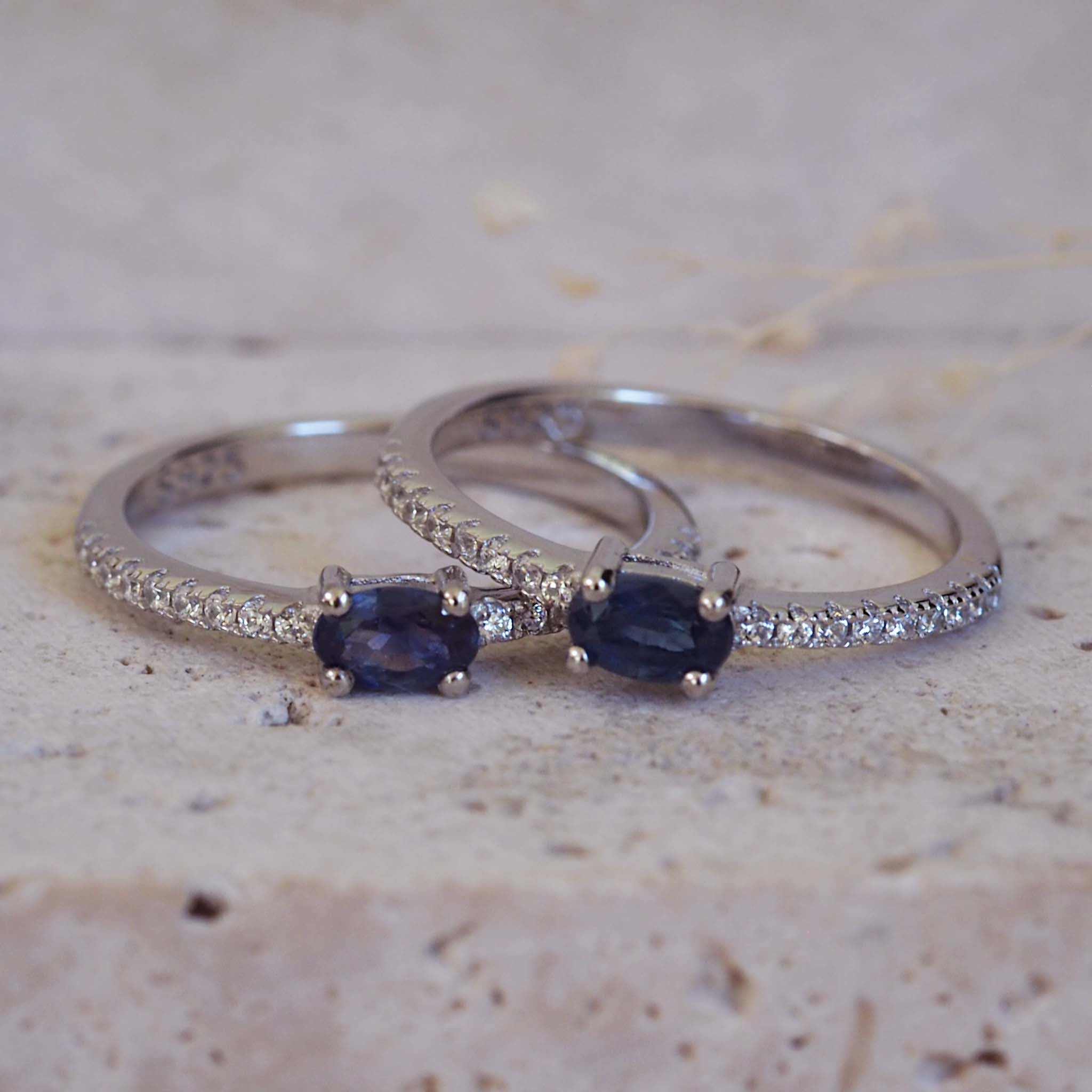 Two silver rings with blue gemstones on a textured surface