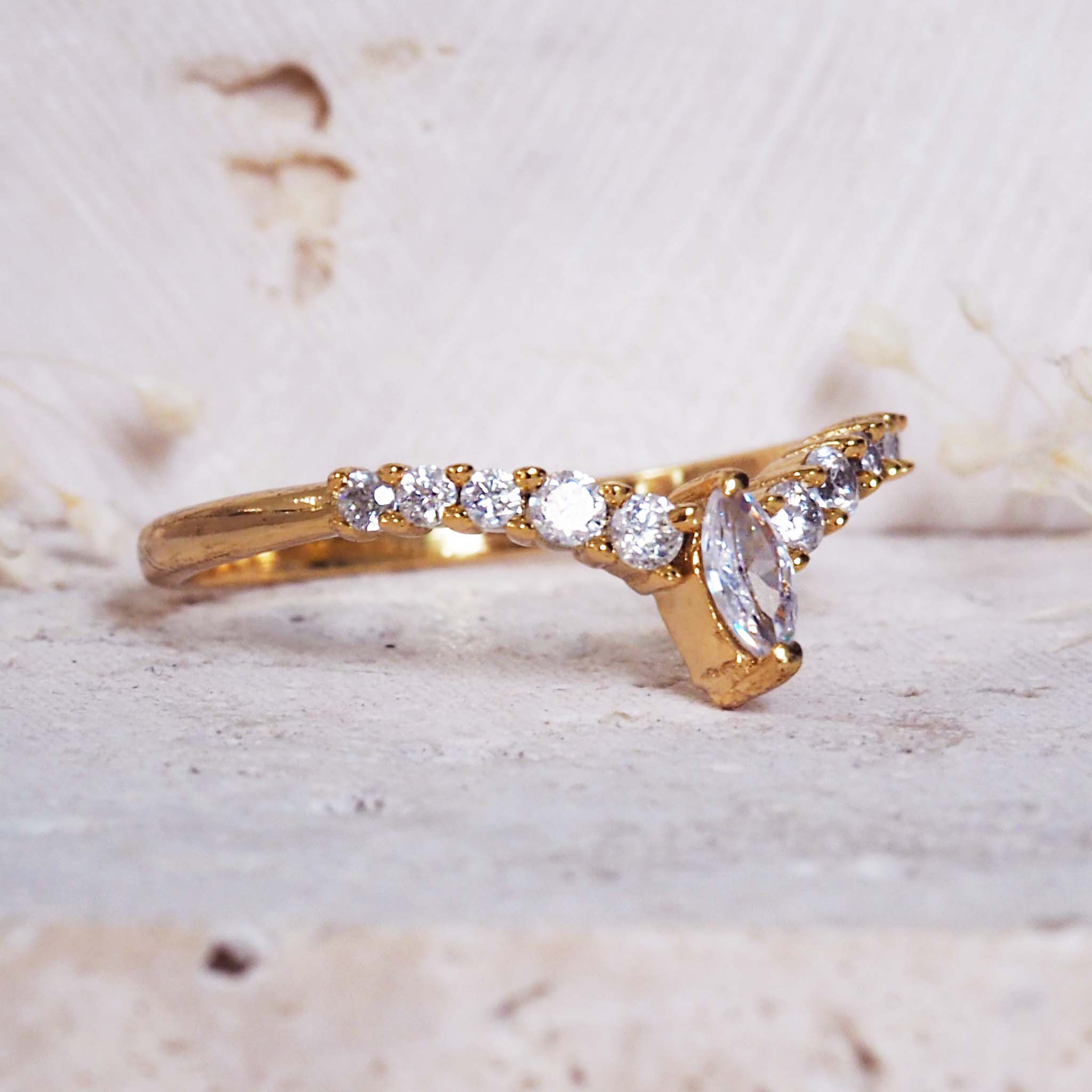 Gold ring with diamonds on a textured beige background