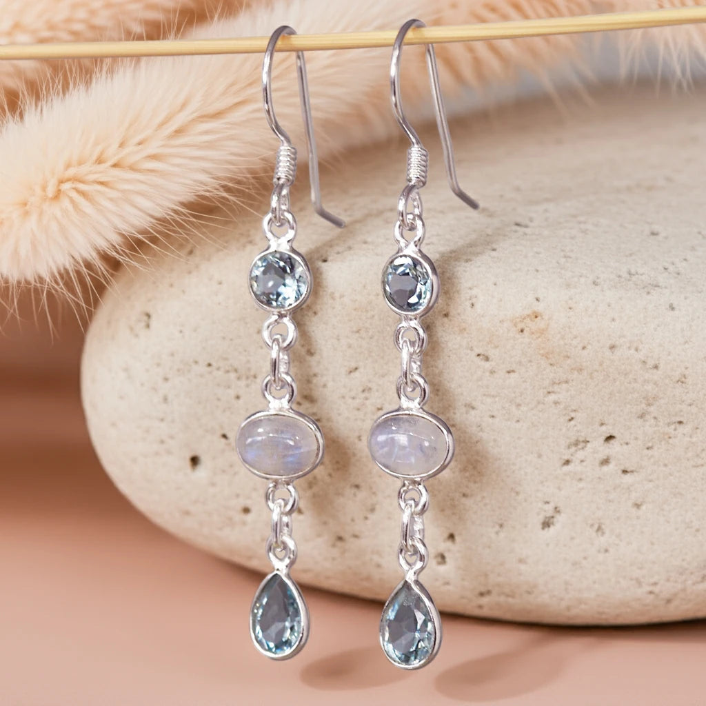 Silver earrings with gemstones on a stone surface