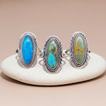 Three silver rings with turquoise stones on a white stone surface