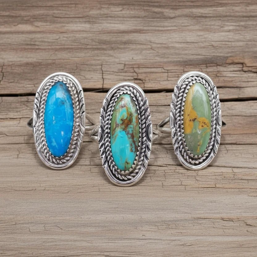 Three silver rings with turquoise stones on a white stone surface