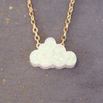 Opal cloud-shaped pendant on a gold chain against a gray background