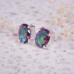 Multicolored gemstone earrings on a light background with dried flowers.