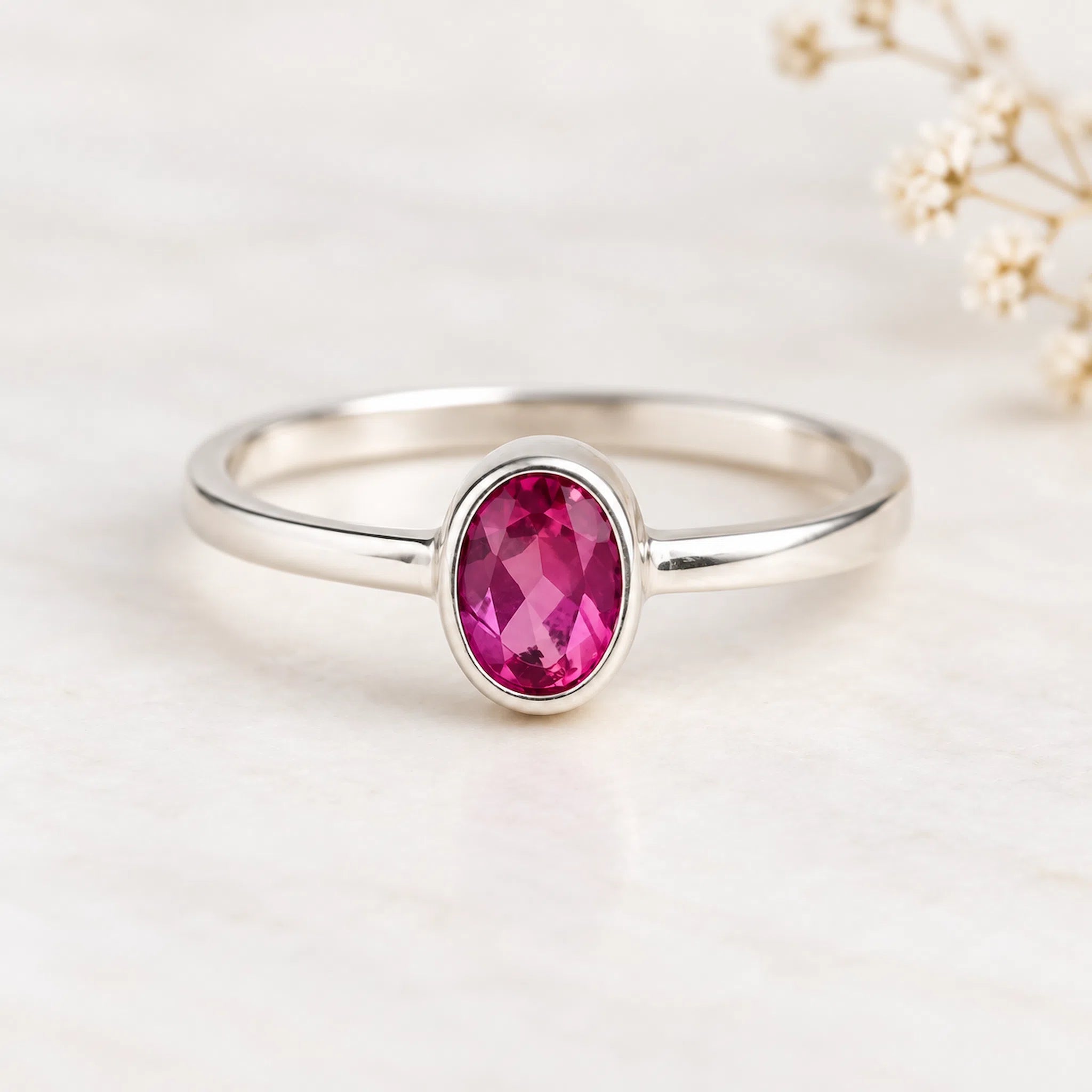 Silver ring with a pink gemstone on a beige background